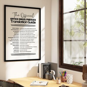 May include: A framed wall art print titled The Official Office Email Phrases Translation Guide, featuring a list of common professional email phrases and their sarcastic interpretations in black text on a white background, displayed in a black frame.
