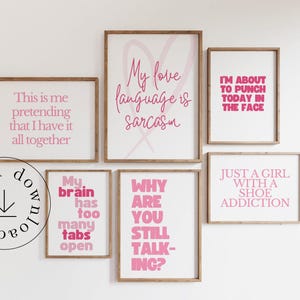 May include: A collection of framed wall art with humorous quotes in pink lettering on a white background. The phrases include "My love language is sarcasm" and "Just a girl with a shoe addiction." The frames are a natural wood color.