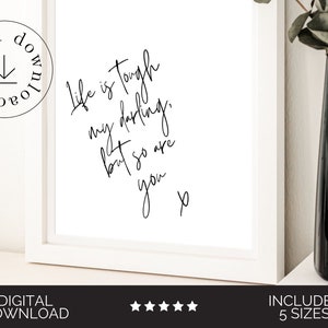 May include: A white framed printable with black calligraphy that reads "Life is tough my darling, but so are you."