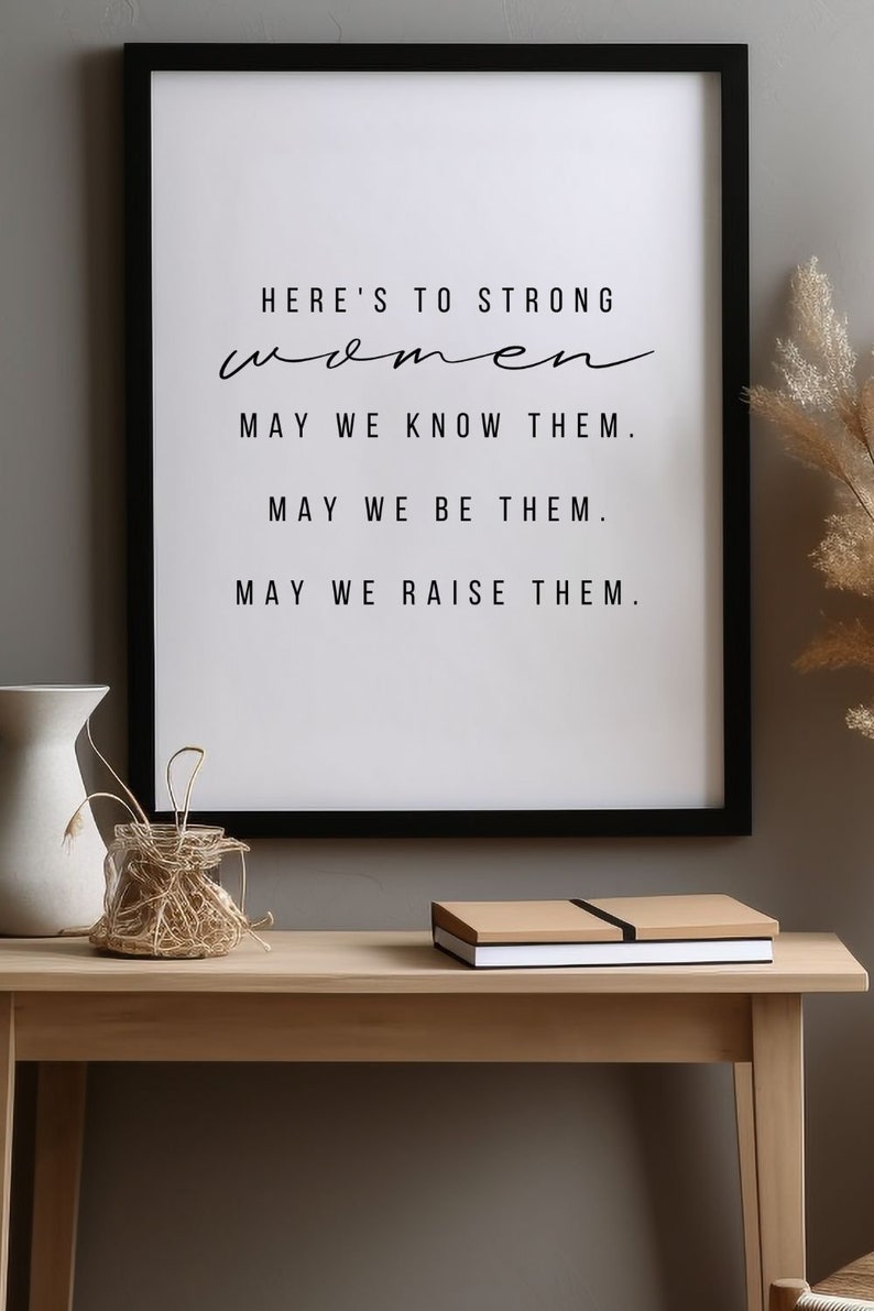 May include: Black framed print with the text "HERE'S TO STRONG women MAY WE KNOW THEM. MAY WE BE THEM. MAY WE RAISE THEM."