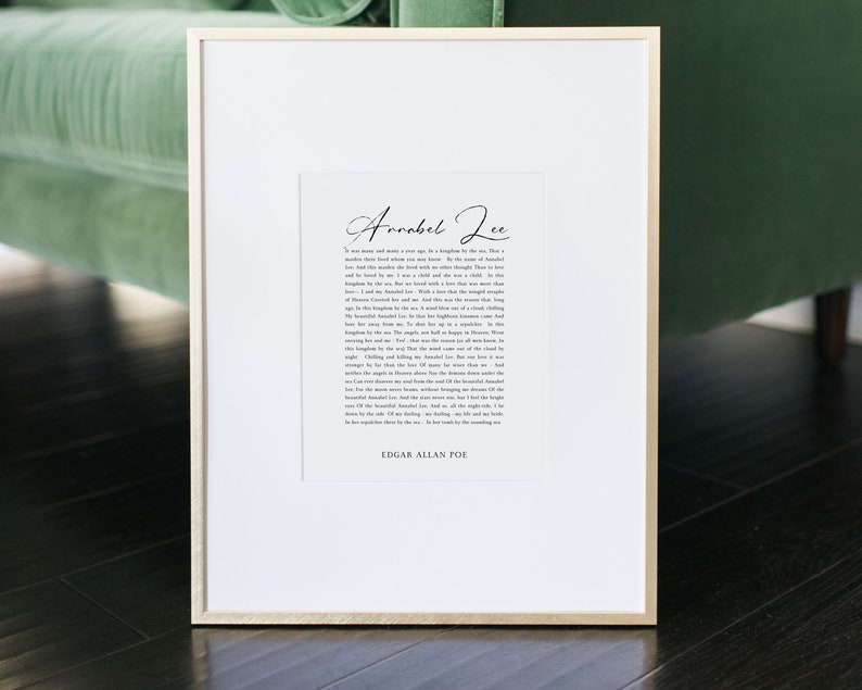 Pu&ograve; includere: Una stampa incorniciata con sfondo bianco e sovrapposizione di testo nero. Il testo recita "Annabel Lee" e include una poesia di Edgar Allan Poe. La cornice &egrave; in legno chiaro.