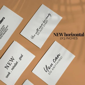 May include: White horizontal cards with black text, including phrases like "daily reminders" and "You can do anything!" The cards measure 2x3 inches. The background is a warm, neutral tone.