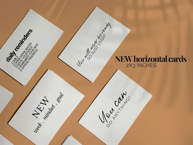 May include: White horizontal cards with black text, including phrases like "daily reminders" and "You can do anything!" The cards measure 2x3 inches. The background is a warm, neutral tone.