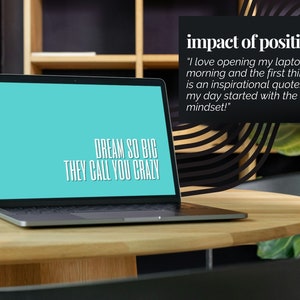 May include: A laptop computer with a blue screen displaying the text "DREAM SO BIG THEY CALL YOU CRAZY". The laptop is on a wooden table in a modern office setting. The text "impact of positivity" is visible in the upper right corner of the image.