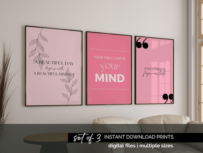 May include: Set of three framed pink art prints with inspirational quotes in black text. The prints are displayed on a white wall above a sofa. The prints include the phrases: "A beautiful day begins with a beautiful mindset", "Your only limit is your mind", and "Everything is figureoutable."