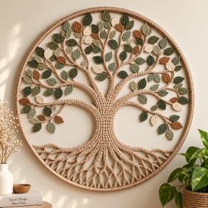 Puede incluir: Un tapiz circular con un diseño de árbol de la vida tejido a ganchillo. El árbol presenta un tronco y ramas gruesas de color beige con numerosas hojas pequeñas y texturizadas en tonos verde salvia, oliva, verde oscuro, crema y marrón óxido.