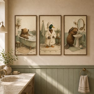 Peut inclure: Un ensemble de trois cadres muraux représentant des animaux anthropomorphes dans une salle de bain. Le premier montre un ours brun dans une baignoire, le deuxième un canard colvert en peignoir, et le troisième un castor devant un lavabo.