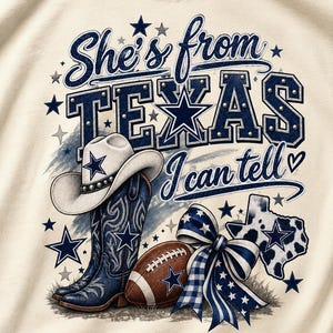 Könnte beinhalten: Ein cremefarbenes Shirt mit einem Aufdruck, der den Text She's from TEXAS I can tell zeigt. Das Design umfasst einen weißen Cowboyhut, blaue Westernstiefel, einen braunen Football, eine blau-weiß gemusterte Schleife und eine Karte von Texas mit einem Stern.