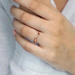 Handmade pure solid copper wave ring on ring finger woman holding wrist white linen shirt close-up soft pink nude nail polish delicate skin texture, thin organic wavy bypass contour band unplated copper high mirror polish ripple chevron stacking boho minimalist ocean wave wishbone ring solid copper Jaipur artisan handmade everyday linen aesthetic pure copper ring gift