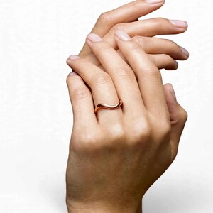 Handmade pure solid copper wave ring on middle finger woman both hands clasped together white studio background natural bare pink nails elegant pose, thin organic wavy bypass contour band unplated copper high mirror polish ripple chevron stacking minimalist boho ocean wave wishbone ring for women dainty surf inspired everyday jewelry Jaipur handmade pure copper clasped hands gift