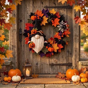 May include: A crochet Halloween wreath featuring a gnome with a black hat, a white beard, and orange pumpkins. The wreath is decorated with colorful autumn leaves, small black bats, and a white spiderweb. Several orange and white pumpkins sit below.