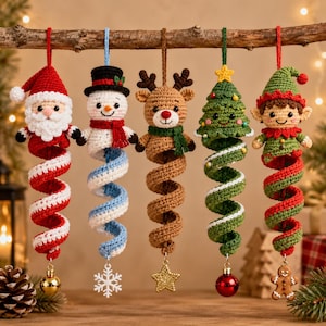 May include: Five crochet Christmas ornaments hanging from a branch. The figures include Santa Claus, a snowman, a reindeer, a Christmas tree, and an elf. Each character features a long, spiraling tail in festive colors, ending with a small charm.