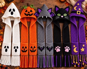 May include: Five crochet hooded scarves featuring Halloween themes: a white ghost, an orange pumpkin, a gray bat with purple wings, a black cat with green eyes, and a purple witch hat with yellow moon and star accents, all with fringe.