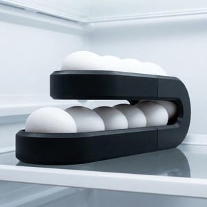May include: A matte black, two-tiered, C-shaped egg holder containing white eggs. The structure features a curved design that holds eggs on both the top and bottom levels, providing a compact storage solution for organizing eggs inside a refrigerator.