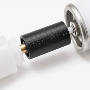 May include: A black cylindrical adapter with the embossed text THERMAFILL connecting a white plastic component to a white canister with a metallic rim. The adapter features a central brass-coloured nozzle and a white plastic stem extending outward.
