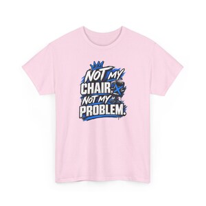 以下が含まれることがあります： 「NOT MY CHAIR, NOT MY PROBLEM.」というテキストがプリントされたライトピンクの半袖Tシャツ。デザインには、青い王冠、青いオフィスチェア、そして白と黒の文字を囲む青いブラシストロークのアクセントが含まれています。