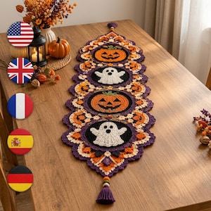 Könnte beinhalten: Ein langer, gehäkelter Halloween-Tischläufer mit abwechselnden kreisförmigen Motiven aus orangefarbenen Kürbissen und weißen Geistern auf schwarzem Grund. Der Läufer hat einen violetten, gewellten Rand und an beiden Enden eine violette Quaste.