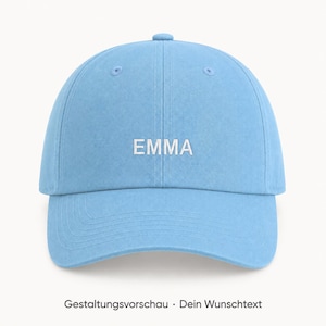 Könnte beinhalten: Eine hellblaue Baseballkappe mit dem Namen EMMA, der in weißen Großbuchstaben auf dem vorderen Mittelteil eingestickt ist. Die Kappe hat eine strukturierte Krone, einen gebogenen Schirm und passende blaue Ösen zur Belüftung.