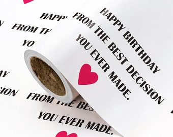 Può includere: Un rotolo di carta da regalo bianca con un motivo ripetuto di testo nero che recita HAPPY BIRTHDAY FROM THE BEST DECISION YOU EVER MADE e piccole icone a forma di cuore rosa pieno stampate sulla superficie della carta.