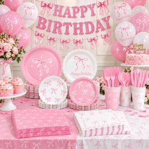 May include: A pink birthday party set featuring a glittery Happy Birthday banner, balloons with bow prints, plates, cups, napkins, and a tablecloth all decorated with white or pink bow patterns, plus a frosted cake and cupcakes.