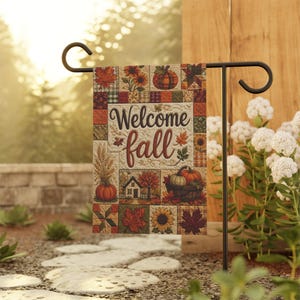 May include: A rectangular garden flag featuring a patchwork design with autumn motifs including pumpkins, sunflowers, and fall leaves. The center displays the text Welcome fall in dark brown script. The flag hangs on a black metal stand.