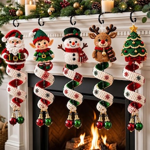 May include: Five crochet Christmas ornaments hanging from black hooks. The figures include Santa Claus, an elf, a snowman, a reindeer, and a Christmas tree. Each figure is attached to a spiraling white and red fabric tail with small jingle bells.