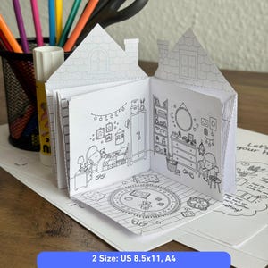 May include: A paper craft house colouring book with black and white line art illustrations of a bedroom interior. The open book displays a bed, wardrobe, dresser, and rug. The text on the page reads 2 Size: US 8.5x11, A4.