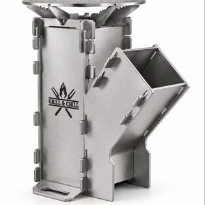 May include: A portable stainless steel rocket stove with a modular interlocking design. The front panel features a black graphic logo with a flame icon, two crossed grilling forks, and the text GRILL & CHILL. It includes a circular top grate.