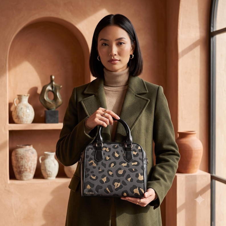 A woman with short dark hair wearing a green coat and beige turtleneck holds a small black handbag with a grey and gold leopard print.