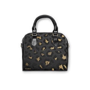 Studio shot of a small structured handbag with black leather trim and handles, displaying a grey and gold leopard print body and the brand name Eloria printed near the bottom.