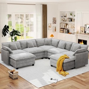 May include: A large, light gray sectional sofa with a modular design, featuring multiple plush seat cushions, back cushions, and square throw pillows. A bright yellow throw blanket is draped over one of the chaise sections of the sofa.