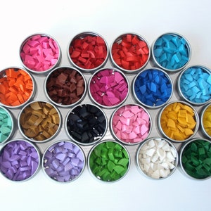 May include: Assortment of 18 small round tins filled with colorful mosaic tiles. The tiles are in various shades of pink, red, orange, brown, green, blue, purple, black, white, and yellow.
