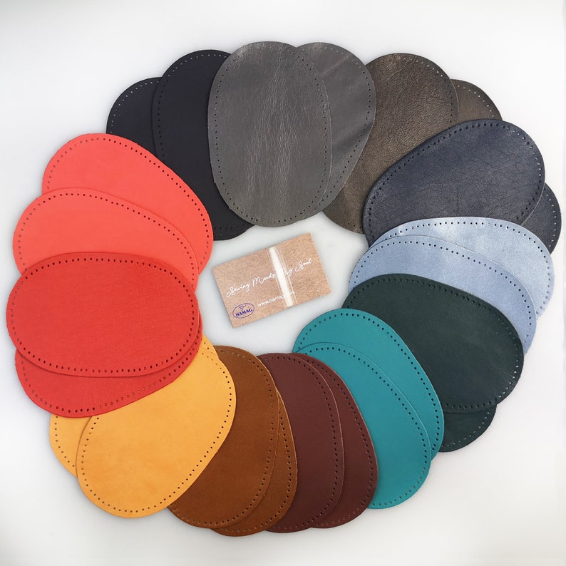 Puede incluir: Un conjunto de 15 parches de cuero ovalados en varios colores, incluyendo rojo, naranja, amarillo, marr&oacute;n, verde, azul y gris. Los parches est&aacute;n dispuestos en un c&iacute;rculo y tienen un borde punteado.