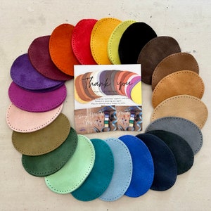 Puede incluir: Una colección de 18 círculos de cuero de gamuza en varios colores, incluyendo morado, rosa, verde, azul, marrón y amarillo. Los círculos están dispuestos en forma de semicírculo con una nota de agradecimiento en el centro. La nota dice "Gracias por su compra".