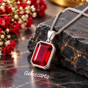 May include: A silver pendant necklace featuring a large, rectangular, emerald-cut red gemstone set in a polished silver frame. The pendant hangs from a delicate silver chain. The text Gemscarts is printed in white on the dark surface below.