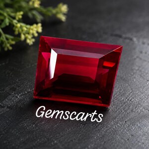 Peut inclure: Une pierre précieuse rectangulaire à facettes d'un rouge profond avec une grande clarté. La pierre présente des bords nets et une surface polie qui reflète la lumière. Le mot Gemscarts est imprimé en blanc sous la pierre sur une surface sombre.