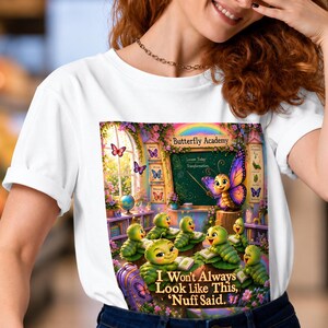 May include: A white t-shirt featuring a colorful graphic of a classroom scene titled Butterfly Academy. The image shows a butterfly teacher instructing green caterpillars with the text, I Won't Always Look Like This, 'Nuff Said.