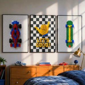 Op de afbeelding: Drie ingelijste wanddecoraties met reliëf van bouwstenen. Links een rode en blauwe raceauto, in het midden een geel handgebaar op een geblokte achtergrond met de tekst LET'S GOOO!, en rechts een groen skateboard.
