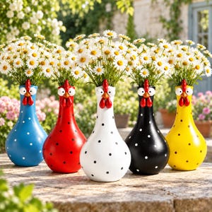 Può includere: Cinque vasi in ceramica a forma di gallina, ciascuno con cresta e bargigli rossi, occhi bianchi e un motivo a pois. I vasi sono blu, rossi, bianchi, neri e gialli e contengono ciascuno un bouquet di margherite bianche con centro giallo.