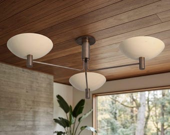 May include: A three-light ceiling fixture featuring a central dark metal stem with three horizontal arms extending outward. Each arm supports a white, bowl-shaped glass shade facing upward, creating a balanced and symmetrical lighting design.
