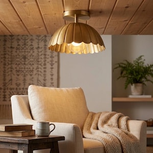 May include: A semi-flush mount ceiling light fixture featuring a scalloped, dome-shaped shade with a brushed brass finish. The light is mounted to a wooden ceiling and contains a single exposed light bulb that emits a warm, soft glow.
