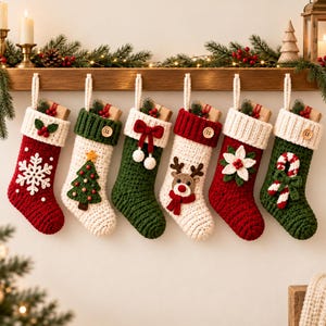 Könnte beinhalten: Sechs gehäkelte Weihnachtsstrümpfe hängen in einer Reihe. Die Strümpfe zeigen verschiedene Motive, darunter eine weiße Schneeflocke, einen grünen Weihnachtsbaum, eine rote Schleife, ein Rentiergesicht, einen weißen Weihnachtsstern und eine rot-weiße Zuckerstange.