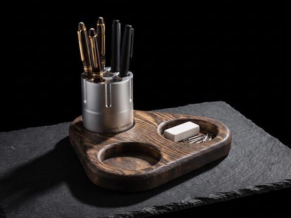 A machined aluminum revolver cylinder that spins to hold your pens — equal parts functional desk organizer and satisfying kinetic fidget object.
