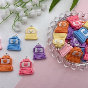 May include: Assortment of colorful miniature laptop charms with a cat face design. The charms are made of plastic and have a shiny finish. They are perfect for adding a touch of whimsy to your keys, bags, or jewelry.