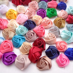 May include: Assortment of small, handmade satin fabric roses in various colors, including pink, blue, purple, red, white, and green. The roses are approximately 1 inch in diameter.