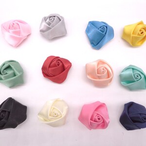 May include: Twelve small fabric rose embellishments in various colors, including pink, blue, green, red, cream, and black.