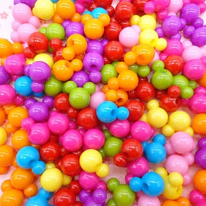Puede incluir: Un gran surtido de cuentas de plástico de colores con forma de cabeza de Mickey Mouse. Las cuentas son de varios colores, incluyendo rojo, naranja, amarillo, verde, azul, morado y rosa.