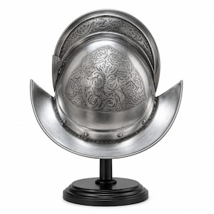 Peut inclure: Un casque morion en métal argenté orné de motifs complexes en relief sur la calotte et les bords. Le casque est monté sur un socle noir circulaire, présentant une finition polie avec des rivets visibles le long de la base.