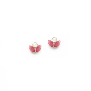 May include: A pair of gold earrings featuring pink and white stones. The earrings are shaped like a flower with two petals and a central stone.