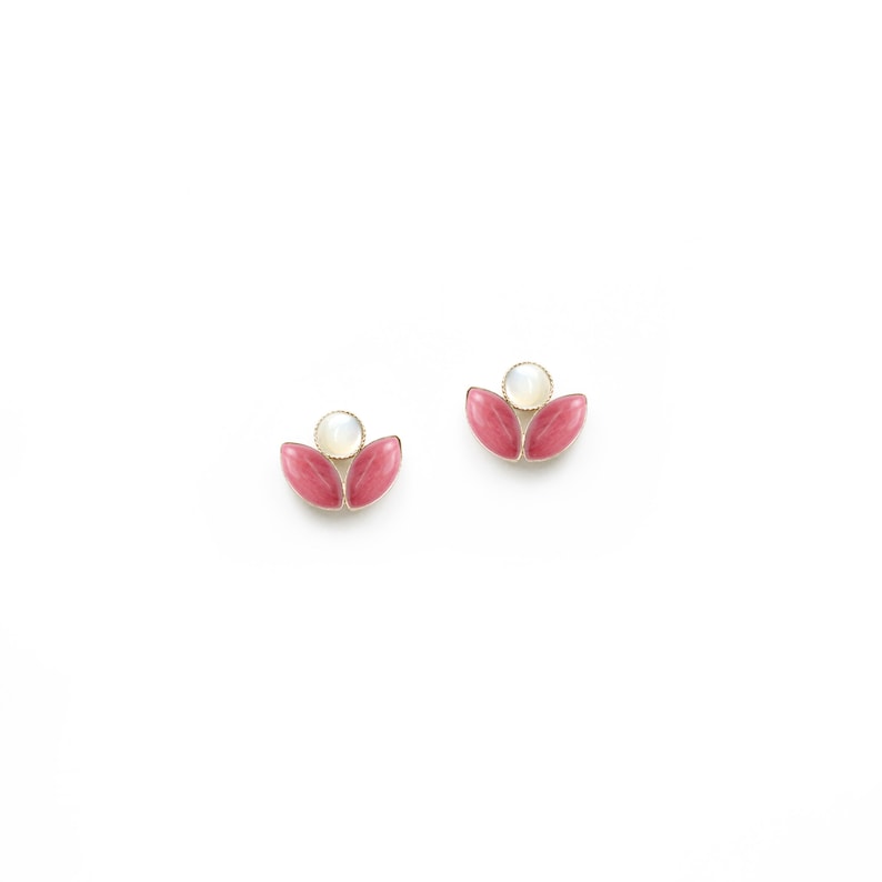 May include: A pair of gold earrings featuring pink and white stones. The earrings are shaped like a flower with two petals and a central stone.